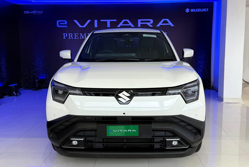 Front three-quarter view of the rugged, premium Suzuki e-Vitara electric SUV finished in metallic gray, showcasing its bold grille and LED headlights.