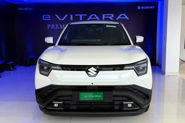 Front three-quarter view of the rugged, premium Suzuki e-Vitara electric SUV finished in metallic gray, showcasing its bold grille and LED headlights.