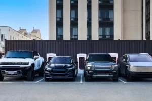A modern, multi-stall public EV charging hub with a mix of DC fast chargers and Level 2 plugs bustling with different electric vehicles in a retail parking lot.