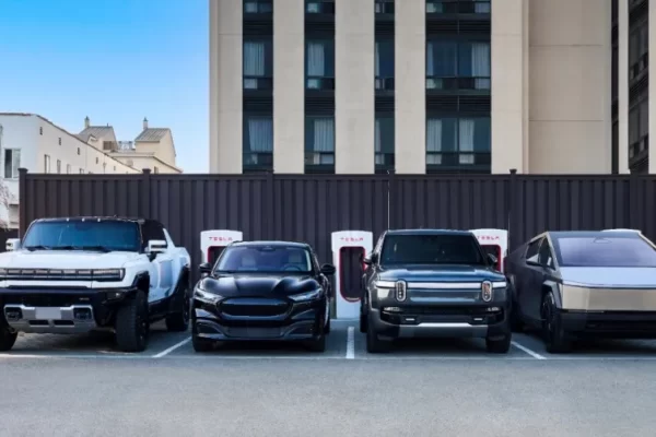 A modern, multi-stall public EV charging hub with a mix of DC fast chargers and Level 2 plugs bustling with different electric vehicles in a retail parking lot.