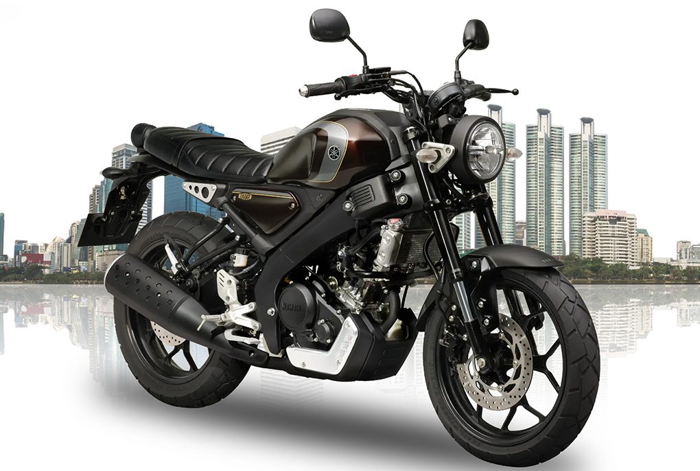 A metallic grey Yamaha XSR 155 parked on an open road highlighting its round retro LED headlamp and teardrop fuel tank.