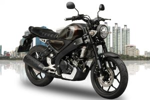 A metallic grey Yamaha XSR 155 parked on an open road highlighting its round retro LED headlamp and teardrop fuel tank.