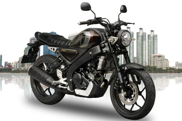 A metallic grey Yamaha XSR 155 parked on an open road highlighting its round retro LED headlamp and teardrop fuel tank.